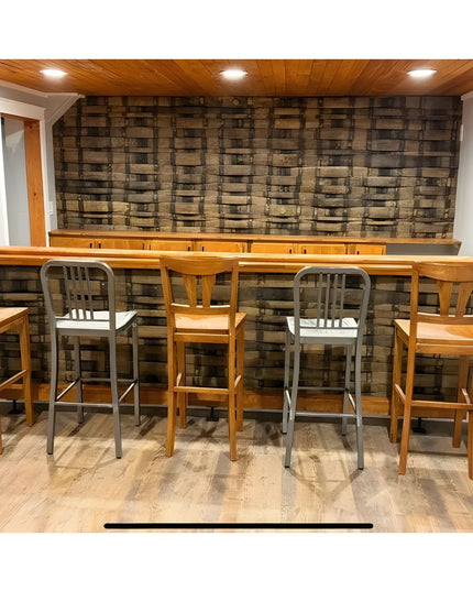 Industrial Farm Co bar foot rail brackets supporting wooden bar counter with metal and wood bar stools against rustic bric...