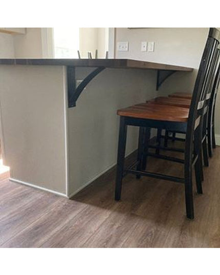 Dark teal metal Lexica 4 inch wide shelf brackets supporting curved wooden countertop with bar stools in modern kitchen by...