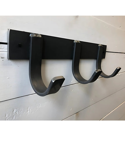 Black metal wall-mounted coat rack with three curved hooks from Industrial Farm Co, The Mary Style design mounted on white...