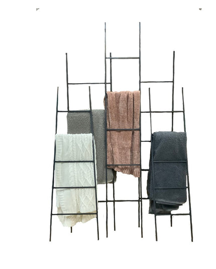 Black metal ladder-style towel rack displaying folded towels and fabrics in sage green, cream, brown, and charcoal colors ...