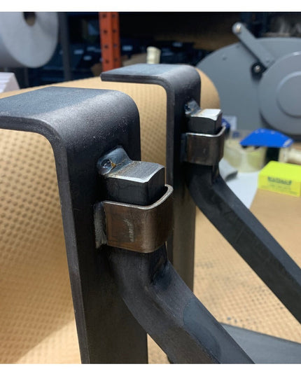 Black steel mantel bracket with square support bar and metal strap mounting system on workbench, heavy duty handmade const...