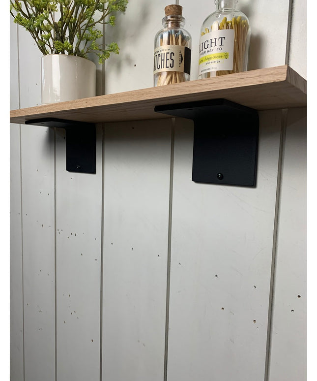 Black steel L-shaped shelf brackets supporting natural wood shelf with decorative bottles and plant vase - Industrial Farm...