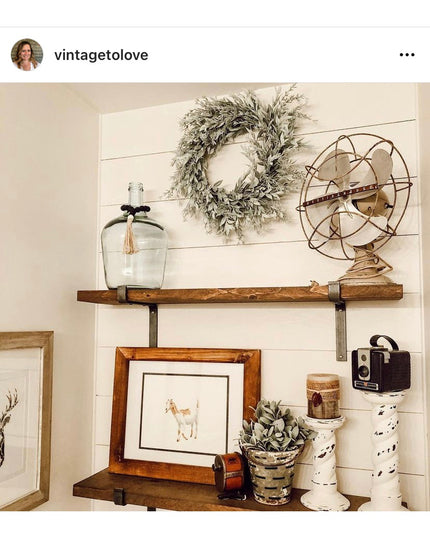 Rustic wooden shelves with black iron Z-style brackets displaying vintage farmhouse decor items against white shiplap wall