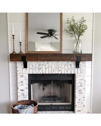 Black metal Seneca 3" Farmhouse Mantel Brackets supporting dark wood beam above white distressed brick fireplace by Indust...
