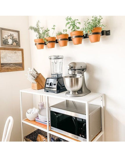 The Yonkers Horizontal Steel Planter by Industrial Farm Co holding terracotta pots with herbs mounted on white kitchen wall
