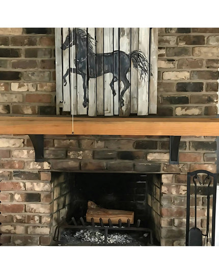 Rustic fireplace with brick surround, wooden mantel, and decorative horse artwork on reclaimed wood panels above