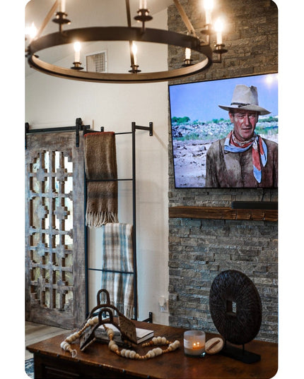 Industrial Farm Co Wall Mounted Ossit Ladder in black metal displayed in rustic living room with stone fireplace and weste...
