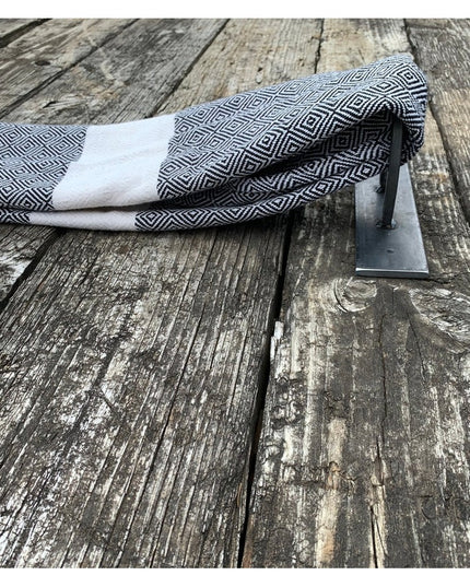 Handmade steel horseshoe towel holder mounted on weathered wood deck with black and white diamond patterned towel - The Gi...