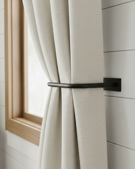 White curtain with a black handle in a room with light-colored walls and a small table with a plant.