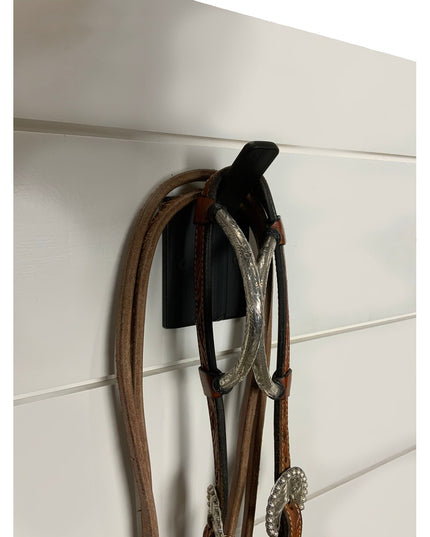 Black Tator Wall Mounted Hook by Industrial Farm Co holding brown leather horse bridle with silver metal details on white ...