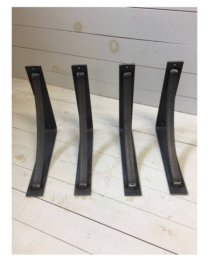 Four black curved steel industrial shelf brackets from Industrial Farm Co displayed on white wooden planks, showing heavy ...