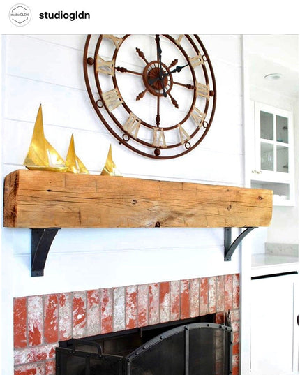 Industrial Farm Co Jeffery Style black metal shelf brackets supporting rustic wooden beam mantel above brick fireplace wit...