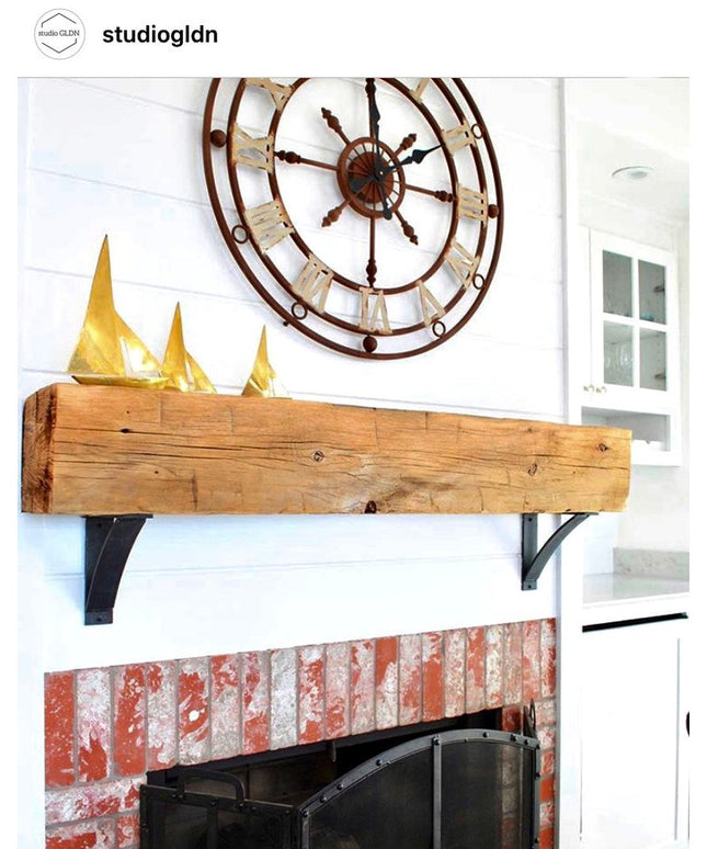 Industrial Farm Co Jeffery Style black metal shelf brackets supporting rustic wooden beam mantel above brick fireplace wit...