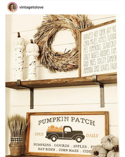 Black metal Z-style shelf brackets supporting rustic wood shelf with fall decor including wheat wreath, white pumpkins, an...