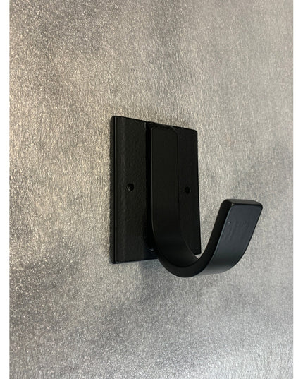 Black metal Dublin Mudroom Hook by Industrial Farm Co mounted on textured white wall, featuring square backplate and curve...