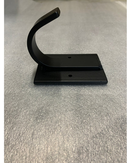 Black metal Dublin Mudroom Hook by Industrial Farm Co with curved design and mounting holes on white textured surface
