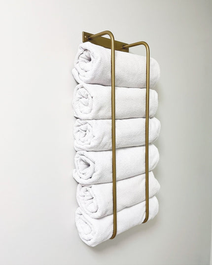 The Tyler Bathroom Towel Rack by Industrial Farm Co - wall-mounted brass metal holder storing six neatly rolled white towe...