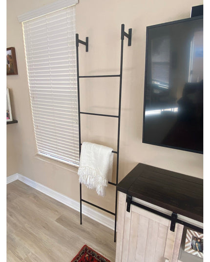 Black metal Brielle Top Mounted Blanket Ladder by Industrial Farm Co with white throw blanket, mounted on beige wall next ...