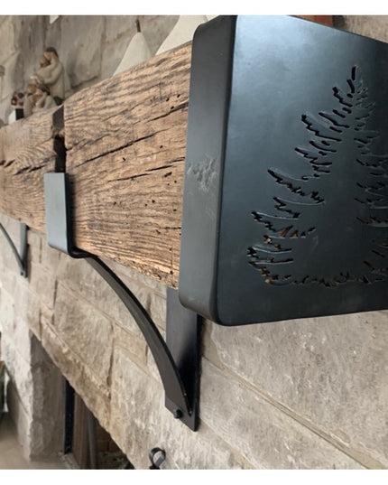 Black metal Vandiver Evergreen Tree Mantel End Caps with fern cutout design mounted on rustic stone fireplace mantel by In...