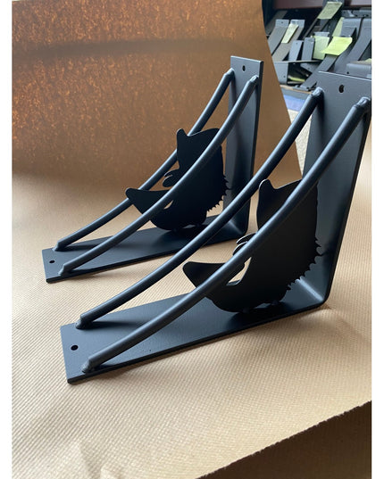 Black metal shelf brackets with large mouth bass fish silhouette cutouts from Industrial Farm Co, showing heavy-duty trian...
