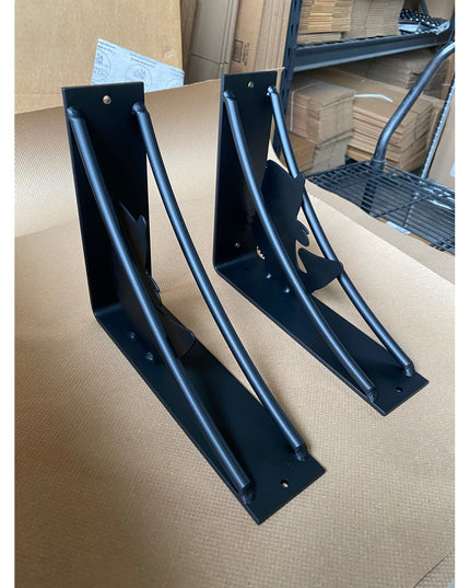 Two black metal heavy-duty large mouth bass shelf brackets with curved support arms displayed on cardboard surface in ware...