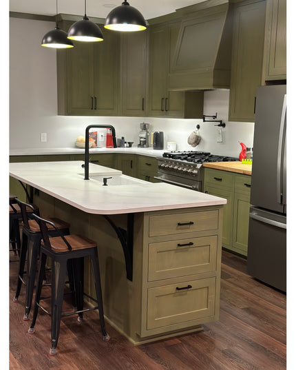 Modern industrial black metal countertop brackets supporting white quartz kitchen island with green cabinets and pendant l...