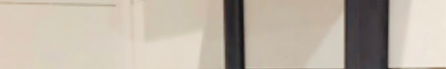 Black metal shelf bracket attached to a wooden shelf against a white wall.