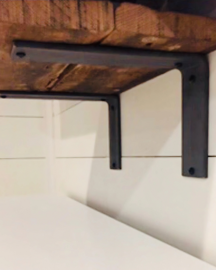 Black metal shelf bracket attached to a wooden shelf against a white wall.