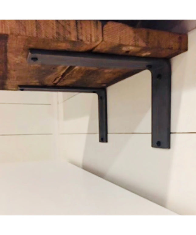 Black metal L-shaped shelf brackets supporting rustic wooden beam against white shiplap wall - The Lucas L Bracket by Indu...