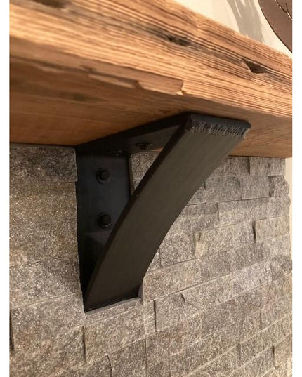 The Eleanor Minimal Steel Bracket by Industrial Farm Co in matte black finish supporting a wood shelf against textured sto...