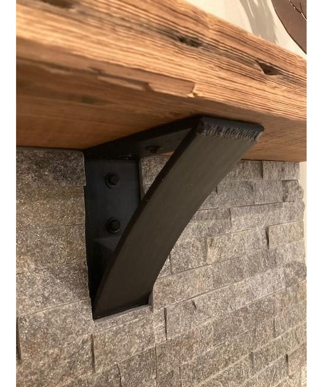 The Eleanor Minimal Steel Bracket by Industrial Farm Co in matte black finish supporting a wood shelf against textured sto...