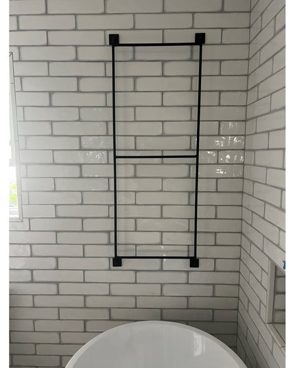 Black metal Arianna Wall Mounted Ladder by Industrial Farm Co displayed against white subway tile bathroom wall above toilet
