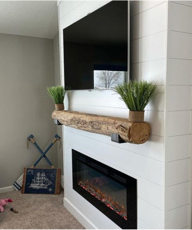 Heavy duty steel J shelf brackets supporting rustic wood beam mantel above white electric fireplace with plants and mounte...