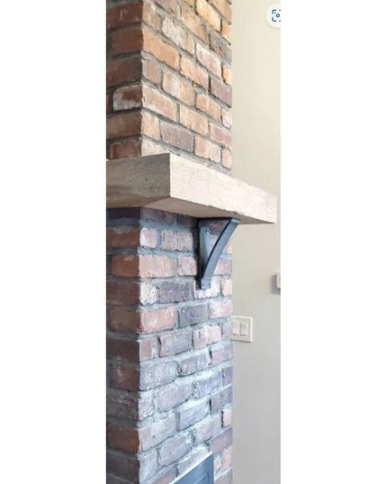 Black metal Jeffery Style Shelf Bracket by Industrial Farm Co supporting wooden mantel on exposed brick fireplace wall