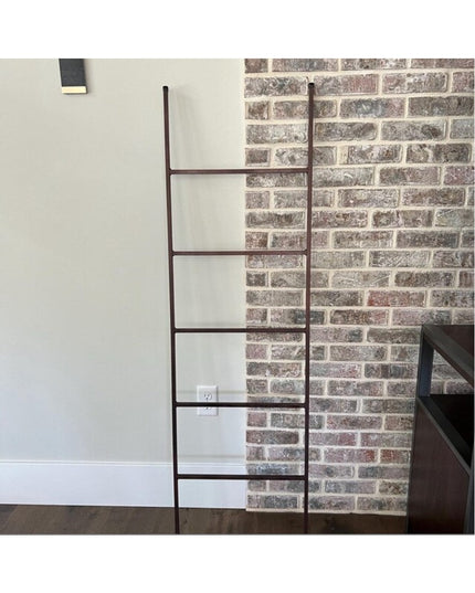 Black metal decorative ladder leaning against brick wall - The Lynn Metal Ladder by Industrial Farm Co in modern interior
