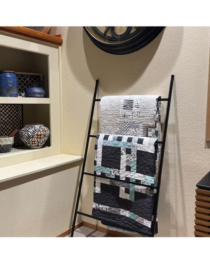 Black metal ladder displaying quilts in modern farmhouse living room with white built-in shelves and decorative pottery - ...