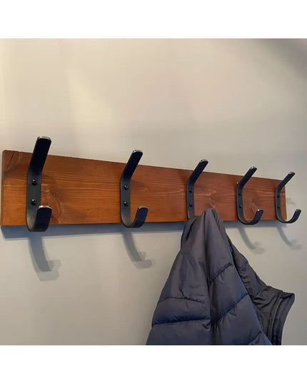 Wood coat rack with five black metal Henrietta 1" Wide Double Hooks from Industrial Farm Co mounted on wall with gray jack...