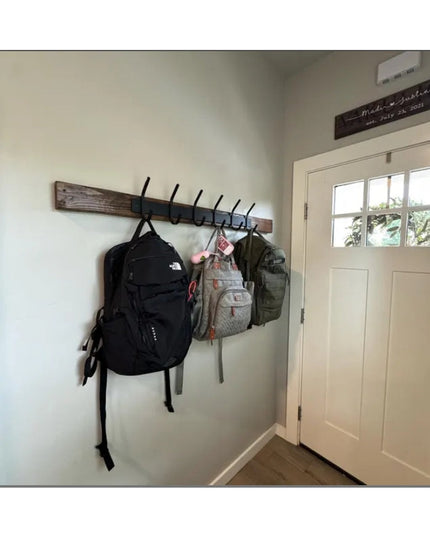 The Eastman Coat & Hook Rack by Industrial Farm Co mounted on white wall with black hooks holding backpacks near white door