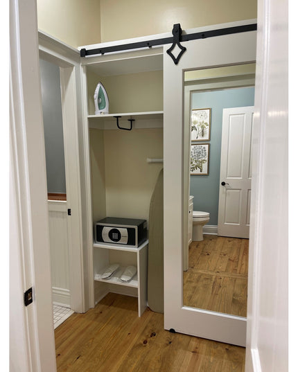 Black metal Split Rock towel bar with diamond-shaped accent mounted in white closet with ironing board shelf and small safe