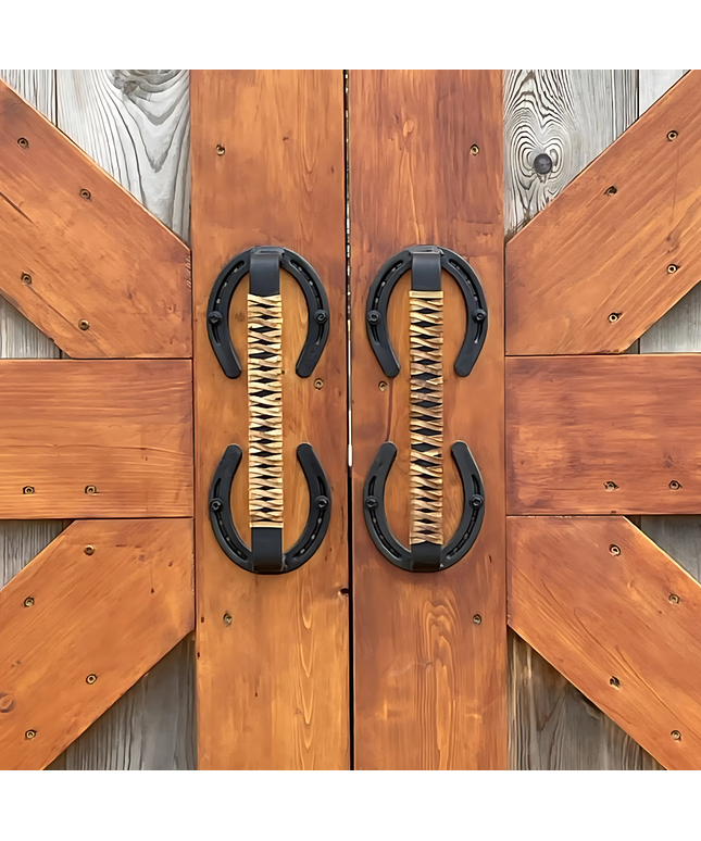 Horse shoe handles wrapped with leather braided handles mounted on barn doors outside.