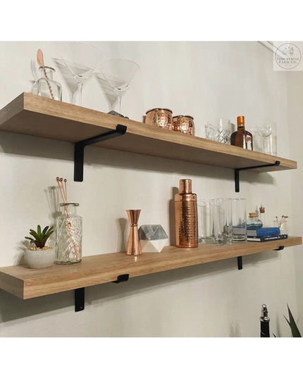 Black metal Z-style shelf brackets supporting natural wood floating shelves displaying copper barware and glassware agains...