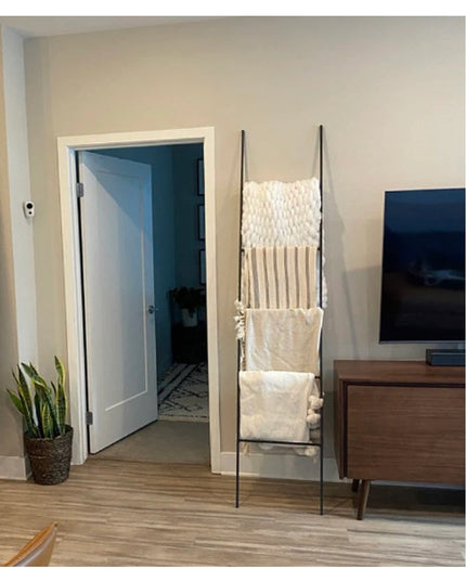 Black metal ladder with white macrame wall hanging and linen storage pockets in modern living room - The Lynn Metal Ladder...