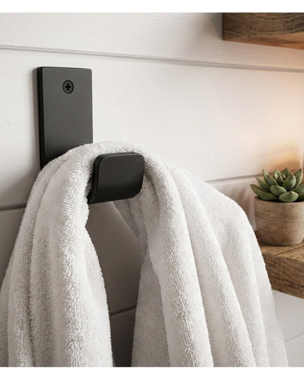 Black metal Western Ridge 1.5" J Wall Hook by Industrial Farm Co mounted on white shiplap wall holding white towel with ca...