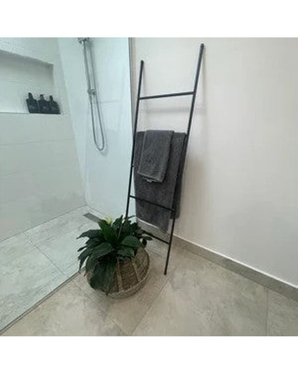 Black metal ladder towel rack leaning against bathroom wall with gray towels and decorative plant basket - The Lynn Metal ...