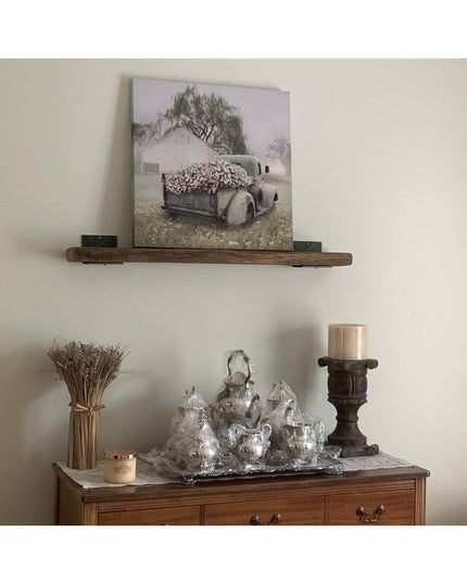 Industrial Farm Co black steel L-bracket shelf supports holding rustic wood shelf with vintage truck artwork and farmhouse...