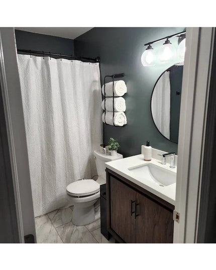 Black metal Tyler towel rack by Industrial Farm Co holding white towels in modern bathroom with dark green walls and white...
