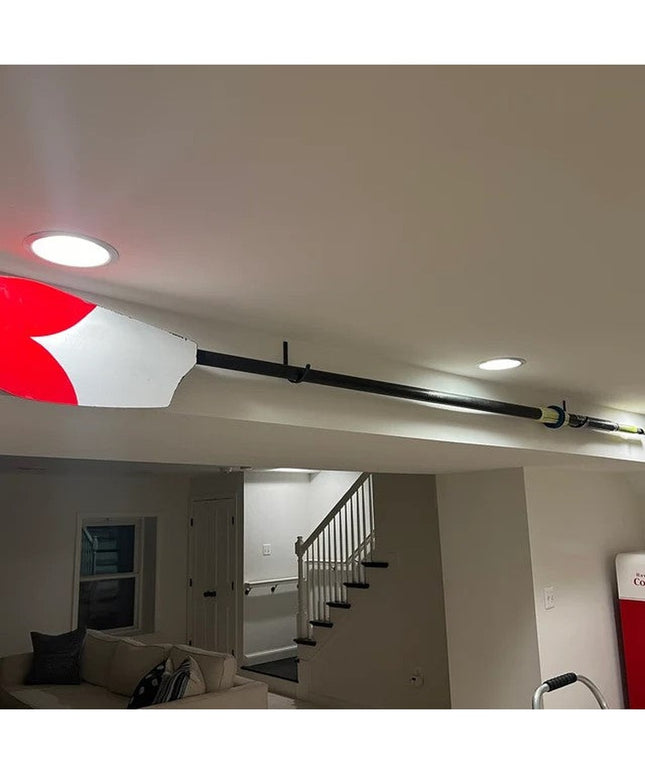 Red and white oar mounted on ceiling with black steel display hooks by Industrial Farm Co in modern basement living room