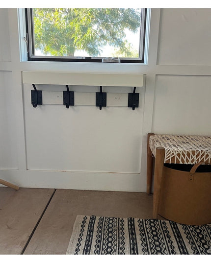 The Felix Wall Hook by Industrial Farm Co - black metal coat hooks mounted on white wainscoting beneath window in modern e...