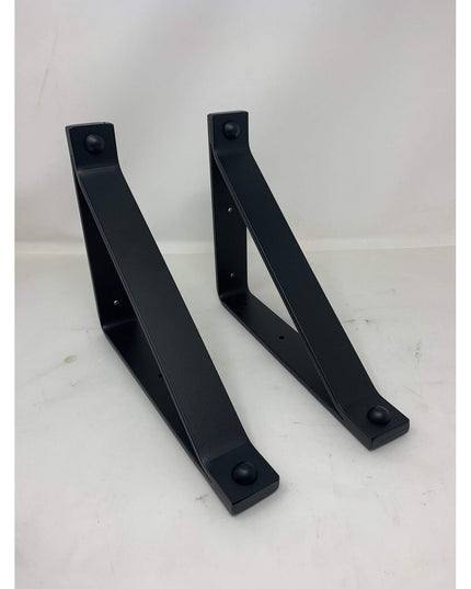 Two black metal Joyce Modern Shelf Supports by Industrial Farm Co with curved triangular design and mounting holes on whit...