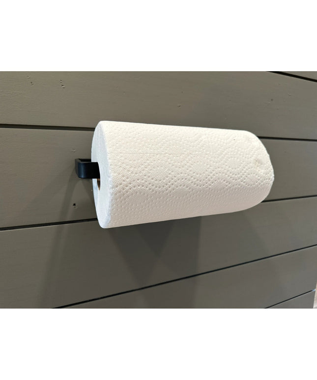 The Jordan Paper Towel Holder by Industrial Farm Co mounted on gray shiplap wall with white paper towel roll and black met...